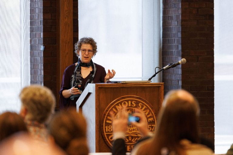 emily bender talking at an ISU podium in front of a crowd of people