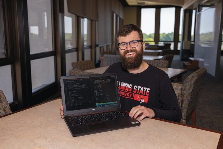 Smiling white male student showing code on his laptop.